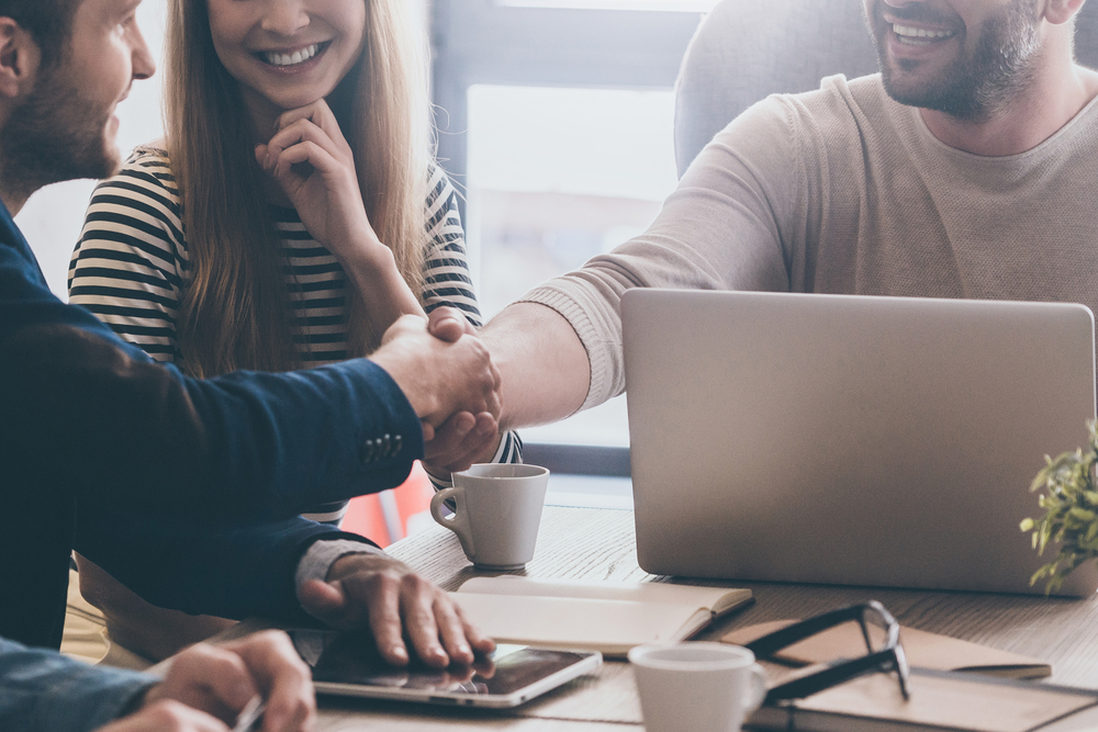 two people shaking hands across a desk